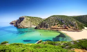 Spiagge della Sardegna: caletta con acque cristalline, sabbia dorata e macchia mediterranea. Un angolo di paradiso che risponde alla domanda: quali sono le spiagge più belle della Sardegna?