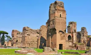 Imponenti rovine delle terme di Caracalla a Roma, con torri di mattoni che si ergono contro il cielo azzurro.