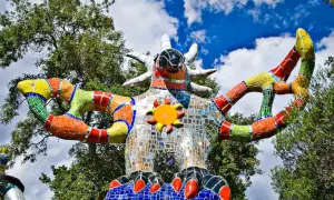 La scultura colorata del Giardino dei Tarocchi in Toscana, con il suo sole radioso e le braccia aperte, sembra accogliere i visitatori in un mondo magico.