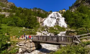 Cascata imponente, un ponte di legno e un sentiero con escursionisti: ecco cosa vedere in Piemonte per un'avventura nella natura.