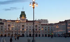 Piazza Unità d'Italia a Trieste, con i suoi palazzi illuminati e un cielo crepuscolare.