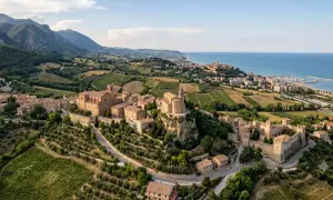 Borghi da visitare vicino Ascoli Piceno: un castello medievale e chiese storiche su colline verdi, con il mare all'orizzonte.