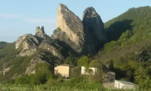I Sassi di Roccamalatina, imponenti formazioni rocciose, dominano un paesaggio verdeggiante con casolari sparsi.