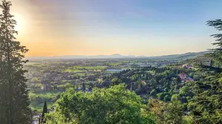 Panoramica della campagna umbra al tramonto, con colline verdi e case sparse. Un'ottima vista per scoprire cosa vedere vicino Perugia.