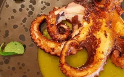 Tentacoli di polpo grigliato su crema verde, un'ottima idea su cosa mangiare ad Agrigento per un'esperienza culinaria indimenticabile.