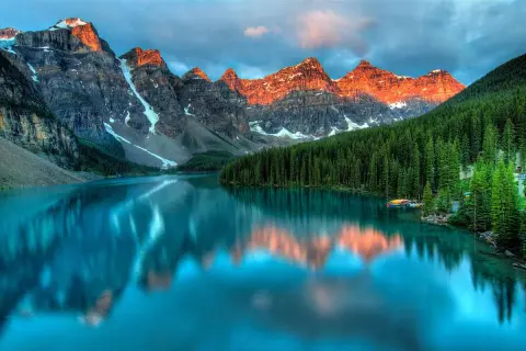 Lago turchese riflette le montagne italiane più famose, con foreste di conifere e cielo nuvoloso.
