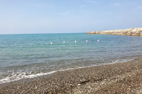 Spiaggia di ciottoli a Cecina, con mare calmo e un molo in lontananza. Perfetto per scoprire cosa vedere e rilassarsi.