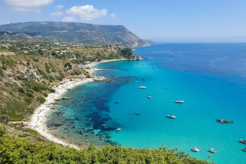Spiaggia dorata, acque cristalline e barche all'orizzonte: ecco cosa fare in Calabria per una vacanza indimenticabile.