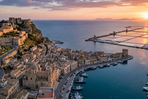 Vista aerea di Trapani al tramonto: castello, porto con barche, saline e mulini. Perfetto per scoprire cosa vedere a Trapani in 3 giorni.