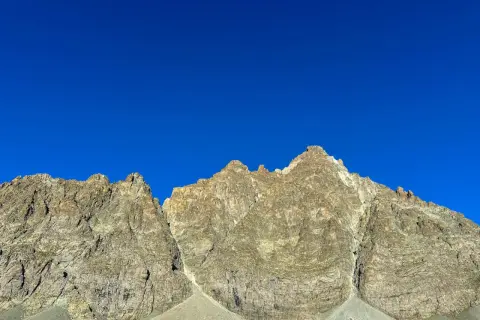 Cime rocciose del Monviso, con la via normale che sale verso la vetta sotto un cielo azzurro intenso.