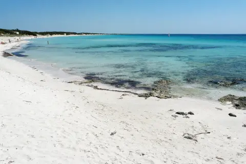 Spiagge Puglia Salento: sabbia bianca finissima, mare cristallino turchese e un velista all'orizzonte. Un paradiso naturale.