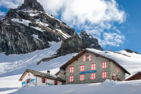 Rifugio Gabiet, uno dei rifugi valle d'Aosta facili, immerso nella neve con montagne imponenti sullo sfondo.