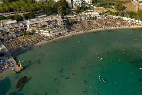 Vasta spiaggia affollata con ombrelloni e bagnanti nel mare cristallino, una delle spiagge più belle del mare di Taranto.