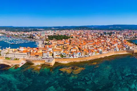 Vista aerea di Alghero, con il porto turistico, le mura storiche e le case dai tetti rossi. Perfetto per scoprire cosa vedere ad Alghero in 3 giorni.
