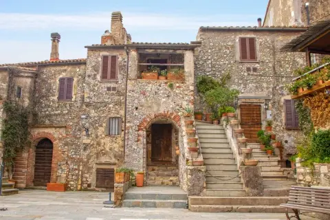 Un angolo di uno dei **borghi più belli della Toscana**, con case in pietra, scale in cotto e piante rigogliose.