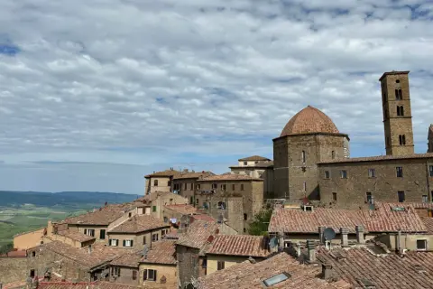 Panoramica di Volterra, con la cupola e il campanile che si stagliano sui tetti rossi. Un paesaggio toscano che ricorda San Gimignano.