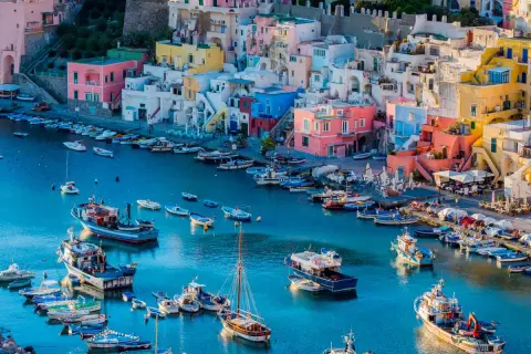 Colorate case a picco sul mare blu, con barche ormeggiate. Un luogo perfetto per escursioni da Napoli.