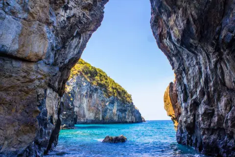 Vista da una grotta su un mare cristallino e una scogliera verdeggiante. Un vero paradiso, tra le scalea spiagge più belle.