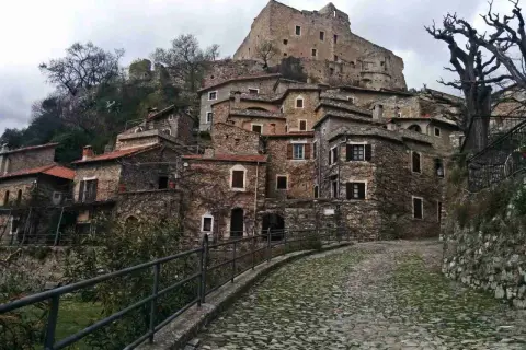 Antico borgo di Castelvecchio di Rocca Barbena, con case in pietra e un castello in cima alla collina.