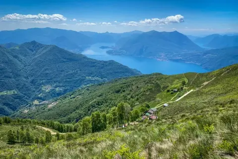Panoramica mozzafiato di un lago alpino e montagne verdi, ideale per passeggiate vicino Milano.