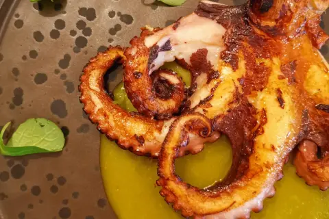 Tentacoli di polpo grigliato su crema verde, un'ottima idea su cosa mangiare ad Agrigento per un'esperienza culinaria indimenticabile.