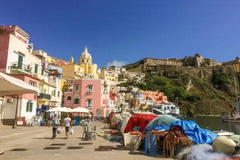Colorate case a picco sul mare, un porto con reti da pesca e la fortezza in collina: ecco cosa vedere a Procida, un gioiello italiano.