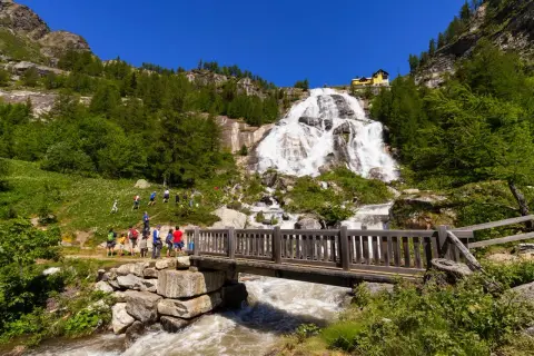 Cascata imponente, un ponte di legno e un sentiero con escursionisti: ecco cosa vedere in Piemonte per un'avventura nella natura.