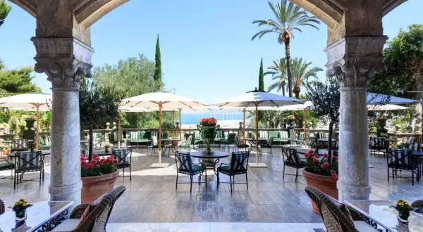 Terrazza con vista mare per un aperitivo a Palermo, tra palme e archi antichi.