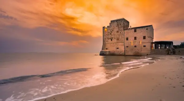 Spiaggia Torre Mozza Follonica: tramonto dorato su antica fortezza sul mare. Come arrivare: facile accesso dalla strada costiera.