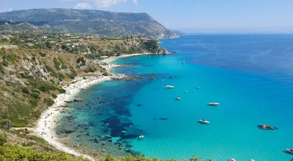 Spiaggia dorata, acque cristalline e barche all'orizzonte: ecco cosa fare in Calabria per una vacanza indimenticabile.