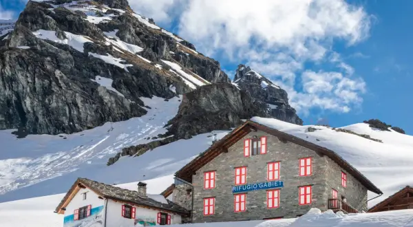 Rifugio Gabiet, uno dei rifugi valle d'Aosta facili, immerso nella neve con montagne imponenti sullo sfondo.