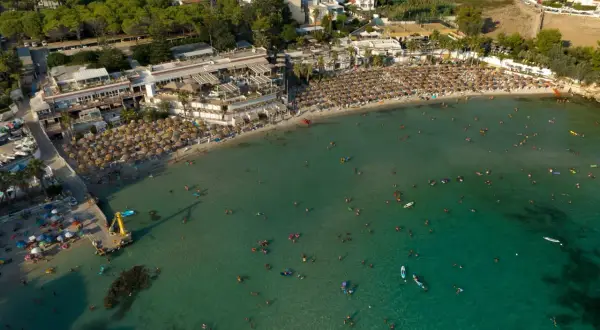 Vasta spiaggia affollata con ombrelloni e bagnanti nel mare cristallino, una delle spiagge più belle del mare di Taranto.