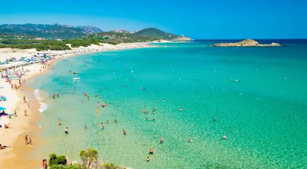 La spiaggia più bella della Sardegna, con sabbia dorata, acque cristalline e tante persone che si godono il sole e il mare.