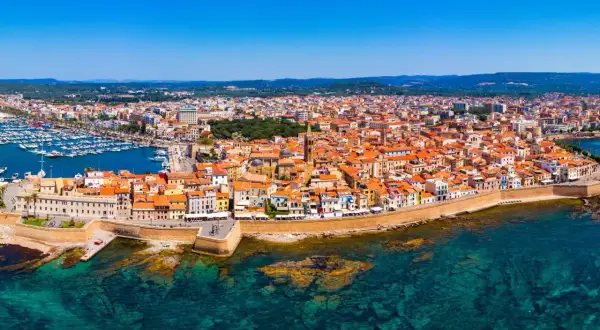 Vista aerea di Alghero, con il porto turistico, le mura storiche e le case dai tetti rossi. Perfetto per scoprire cosa vedere ad Alghero in 3 giorni.