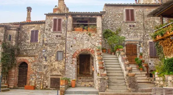 Un angolo di uno dei **borghi più belli della Toscana**, con case in pietra, scale in cotto e piante rigogliose.