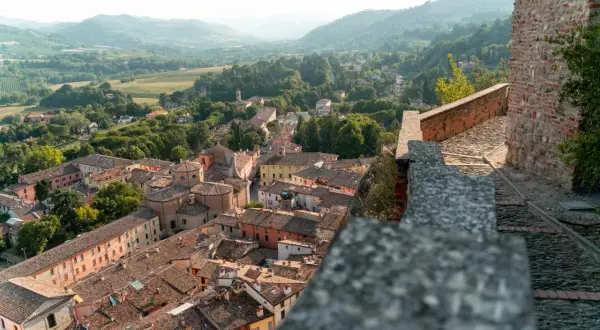 Panoramica di un borgo da visitare in Romagna, con tetti in cotto e colline verdi sullo sfondo.