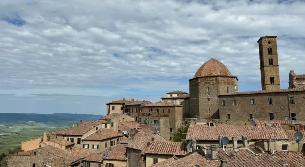 Panoramica di Volterra, con la cupola e il campanile che si stagliano sui tetti rossi. Un paesaggio toscano che ricorda San Gimignano.