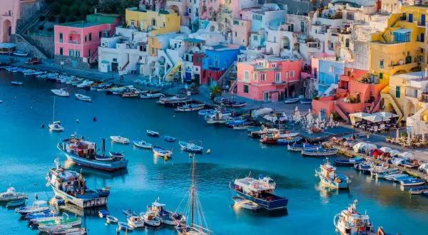 Colorate case a picco sul mare blu, con barche ormeggiate. Un luogo perfetto per escursioni da Napoli.