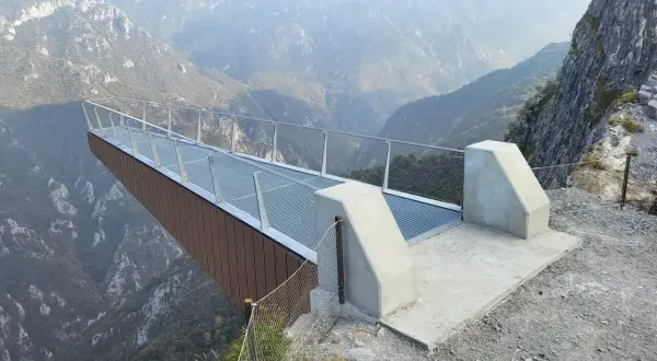 La passerella panoramica "Becco di Dossena" si protende su un profondo canyon, offrendo una vista mozzafiato sulle montagne circostanti.