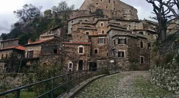 Antico borgo di Castelvecchio di Rocca Barbena, con case in pietra e un castello in cima alla collina.