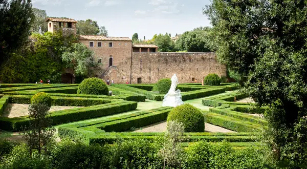 Giardini all'italiana con siepi geometriche e una statua, un assaggio di cosa vedere a San Quirico d'Orcia.