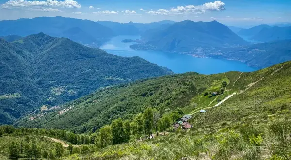 Panoramica mozzafiato di un lago alpino e montagne verdi, ideale per passeggiate vicino Milano.