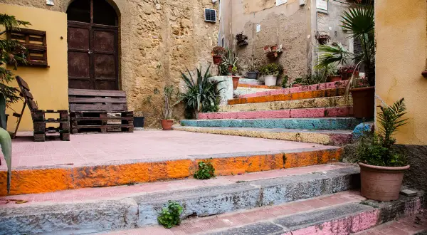 Scalinata colorata, un angolo pittoresco tra le cose da vedere ad Agrigento, con piante e arredi in pallet.