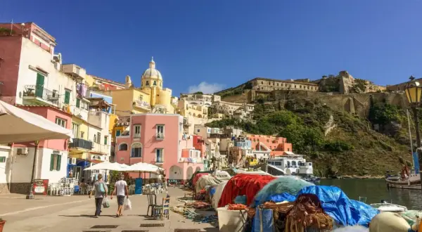 Colorate case a picco sul mare, un porto con reti da pesca e la fortezza in collina: ecco cosa vedere a Procida, un gioiello italiano.