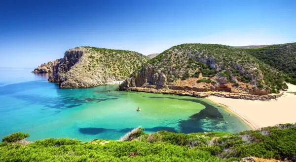 Spiagge della Sardegna: caletta con acque cristalline, sabbia dorata e macchia mediterranea. Un angolo di paradiso che risponde alla domanda: quali sono le spiagge più belle della Sardegna?