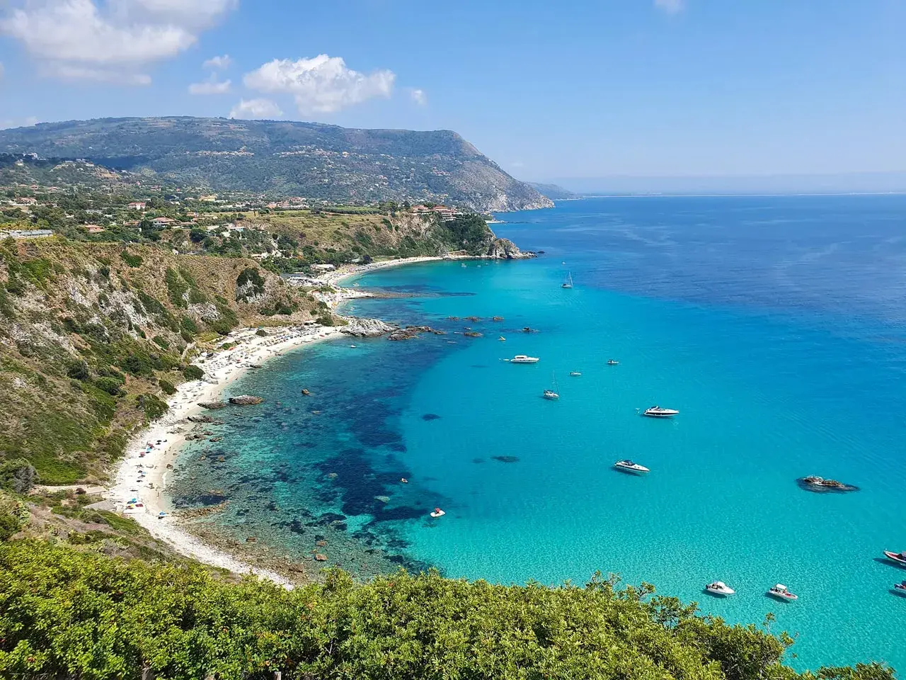 Spiaggia dorata, acque cristalline e barche all'orizzonte: ecco cosa fare in Calabria per una vacanza indimenticabile.