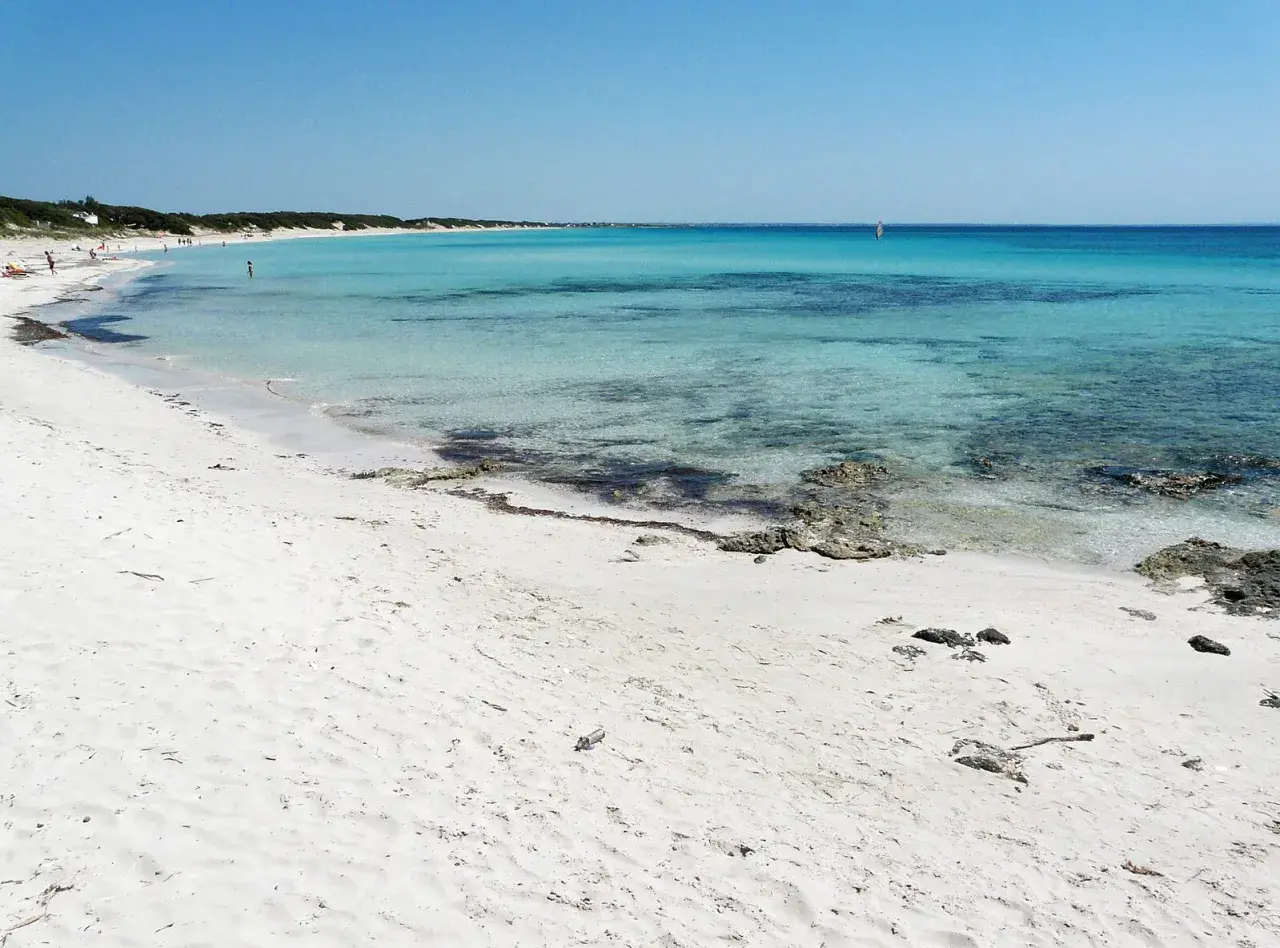 Spiagge Puglia Salento: sabbia bianca finissima, mare cristallino turchese e un velista all'orizzonte. Un paradiso naturale.