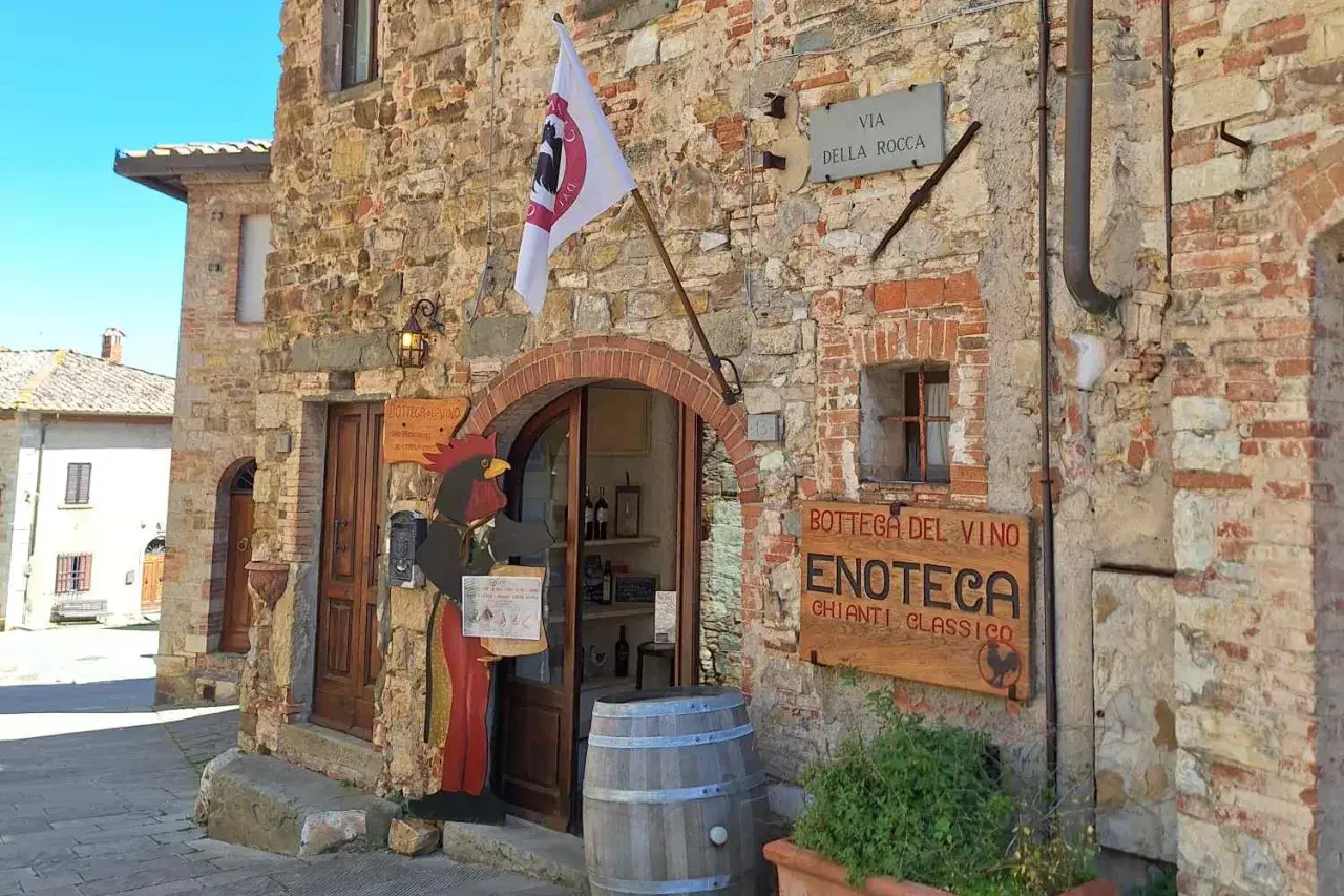 Un'enoteca in Chianti, cosa vedere: un gallo di legno accoglie i visitatori in questa bottega del vino con insegna "Chianti Classico".