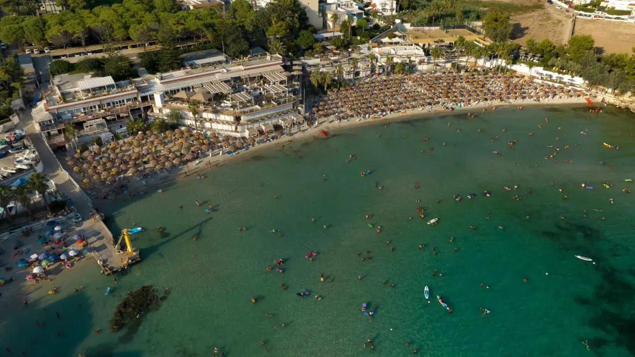Vasta spiaggia affollata con ombrelloni e bagnanti nel mare cristallino, una delle spiagge più belle del mare di Taranto.