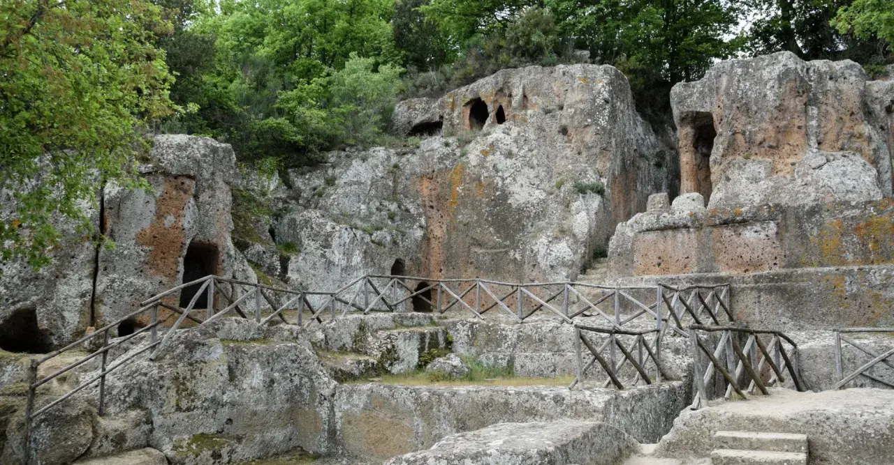 Antiche tombe etrusche scavate nella roccia, con sentieri e recinzioni in legno. Un suggestivo scorcio della mappa dei siti etruschi in Toscana.
